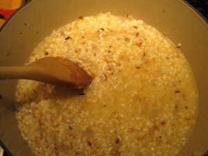 risotto being stirred in saucepan with shallots and white wine
