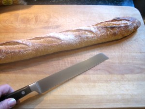 baguette on cutting board with serrated knife