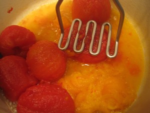 mashing cooked roma tomatoes for homemade tomato soup