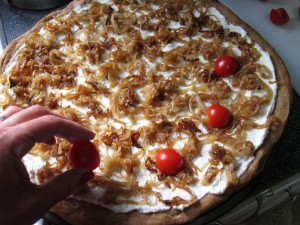 Placing cherry tomatoes on onion tart